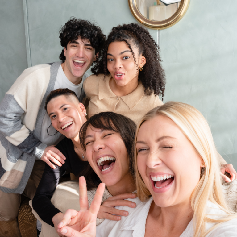 Group of friends of all ethnicities taking a photo as a visual demonstration of the happiness that comes from self-love